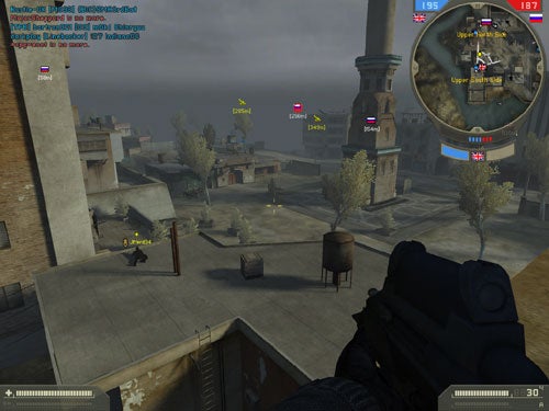 Screenshot of 'Battlefield 2: Special Forces' gameplay showing a first-person view with a player holding a gun overlooking a virtual battlefield with structures, other players, and game interface elements such as a map and scores.
