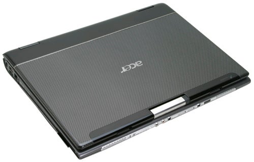 Acer TravelMate 8204WLMi notebook closed and viewed from top angle, showing dark carbon fiber textured cover with Acer logo.