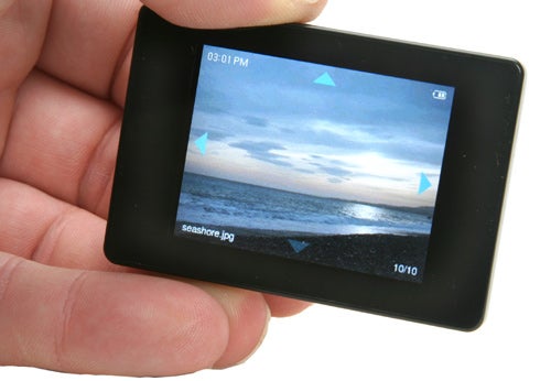 A person holding an iRiver U10 Digital Media Player displaying a photo of the seashore on its screen.