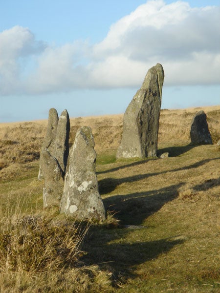 Ancient standing stones in a grassy field with shadows