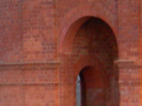 Blurry image of a brick structure with an arched doorway, possibly taken with a Nikon CoolPix P1 Wi-Fi Compact Camera to demonstrate camera focus issues or user error.