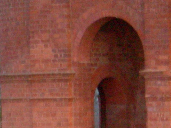 A close-up, low-resolution image of a red brick archway with noticeable pixelation that may illustrate the performance of the Nikon CoolPix P1 camera in low-light conditions or at high zoom levels.
