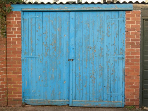 Blue weathered double doors on a brick building.
