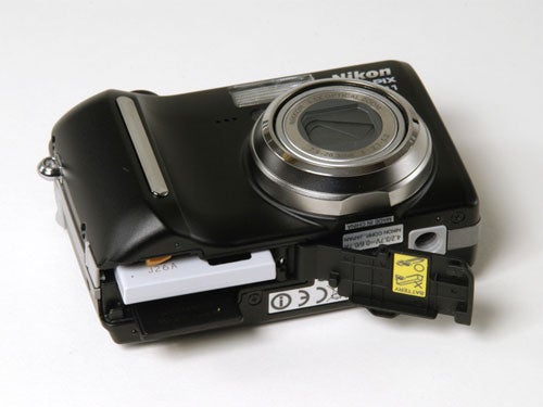 Nikon CoolPix P1 Wi-Fi compact camera with its battery compartment open, showing the battery and memory card slots.