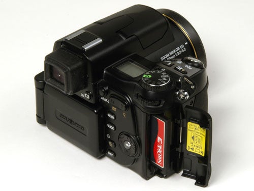 Nikon CoolPix 8800 digital camera with lens extended and memory card slot open showing a red SanDisk CompactFlash card.