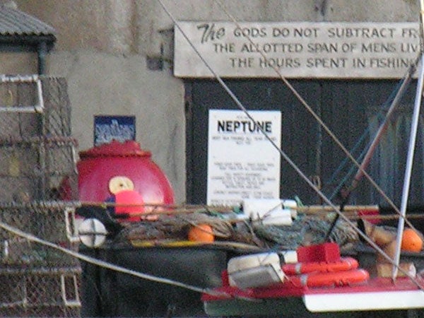 Close-up of assorted fishing gear and buoys on the deck of a boat with a sign reading 