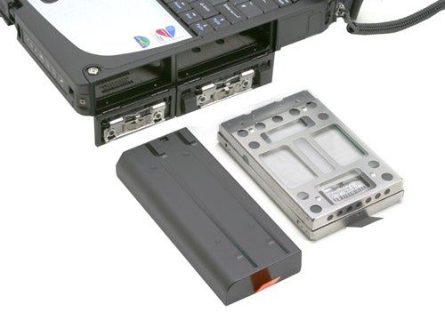 Panasonic ToughBook CF-18 rugged notebook shown with detachable components, including hard drive in protective case and battery pack.
