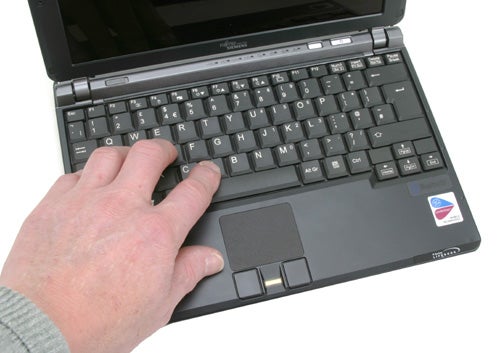 A person's hand resting on the keyboard of a Fujitsu-Siemens Lifebook P7120 laptop with the screen visible in the background.