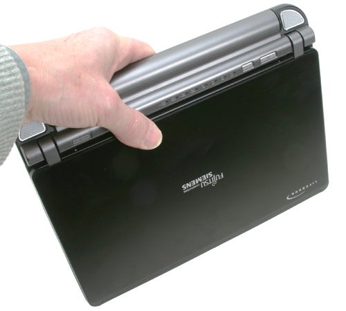 A person holding a Fujitsu-Siemens Lifebook P7120 laptop with one hand, showcasing its portability and compact size.