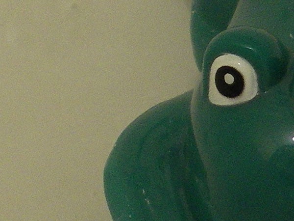 Close-up image of a green rubber duck taken underwater showing the detail of its eye and beak, demonstrating the camera's macro capabilities in a waterproof environment.