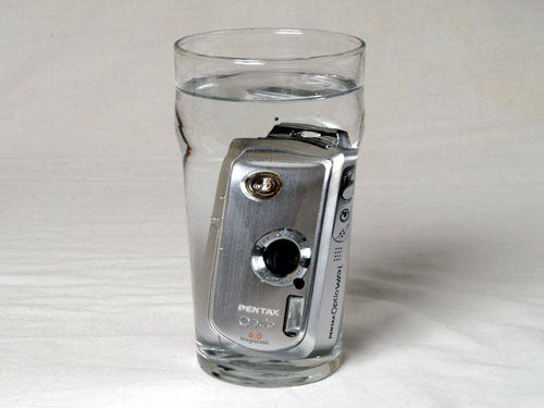 Pentax Optio WPi waterproof camera submerged in a glass of water, demonstrating its water-resistant feature.