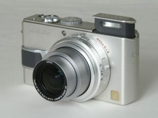 Panasonic Lumix DMC-LX1 digital camera with silver body and extended Leica lens displayed on a neutral background.