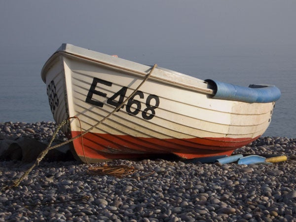 A high-resolution photograph of a white and red boat with registration number E468 resting on a pebble beach under hazy sky conditions, likely taken with a Panasonic Lumix DMC-LX1 camera to demonstrate image quality.