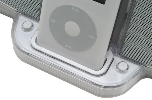 Close-up image of a classic white iPod nestled in an Acoustic Authority iRhythms iPod Speaker Dock, with visible control buttons and speaker mesh detail.