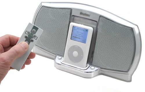 Hand holding a remote control in front of an Acoustic Authority iRhythms iPod Speaker Dock with an iPod mounted on it.