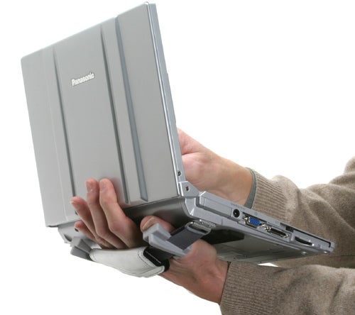 Person holding a silver Panasonic ToughBook CF-W4 laptop with one hand, showing its rugged design and ports on the side.