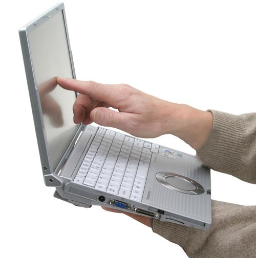 A person holding a Panasonic ToughBook CF-W4 laptop with one hand while pointing at the screen with the other hand.