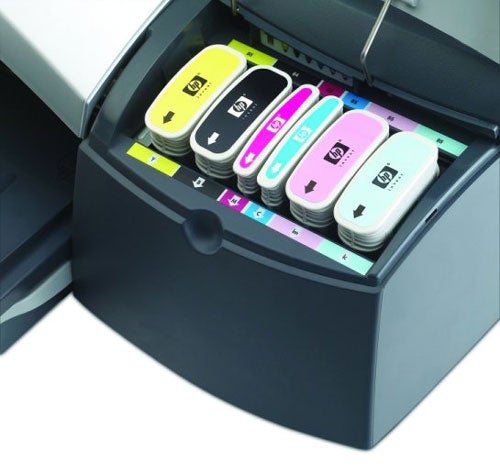 Close-up of HP DesignJet 90r printer's open ink cartridge compartment showing six individual ink cartridges in yellow, cyan, magenta, light magenta, light cyan, and black.