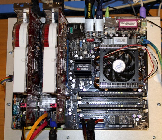 Asus A8R32-MVP Deluxe motherboard with dual graphics cards and CPU cooler installed, showing memory slots, various connectors, and the motherboard layout on a desk.