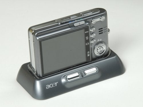 Acer CU-6530 digital camera positioned on a docking station with Acer logo visible, displaying the camera's large LCD screen and control buttons.