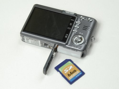 Acer CU-6530 digital camera lying next to a 64MB SD memory card on a white surface.