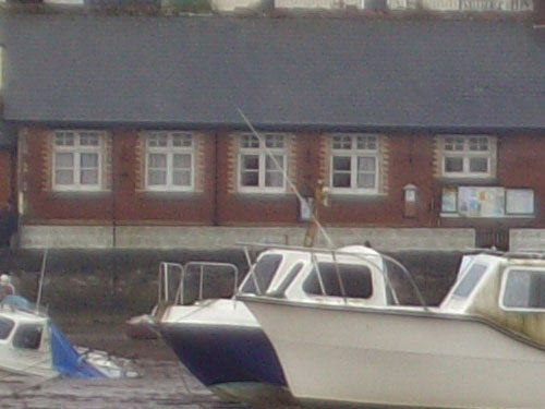 Acer CU-6530 camera sample image featuring a slightly blurry photograph of boats docked near a shore with a building in the background.