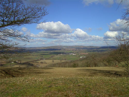 Landscape photograph showcasing the clarity and color representation of the Acer CU-6530 camera. The image features a panoramic view of a valley with various shades of green, a town in the distance, and a dynamic sky with puffy clouds.