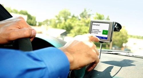 Driver in a vehicle using the Garmin nuvi 350 GPS navigator, which is mounted on the windshield and displaying a map with directions.