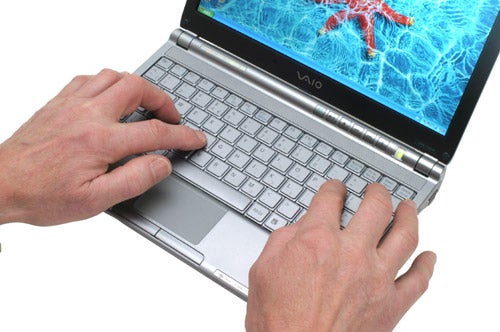 A person typing on a Sony VAIO VGN-TX2XP laptop, which has a silver keyboard and the VAIO logo visible on the display bezel.