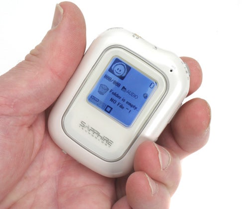 A hand holding a compact Sapphire Ivory 512MB MP3 Player with a blue-lit screen displaying the menu options.