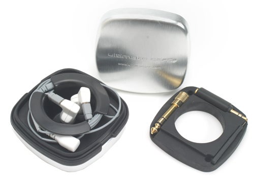 Ultimate Ears super.fi Pro In-Ear Headphones with white earbuds and black cables displayed next to its metal carrying case and a black foam insert with a gold-plated 3.5 mm audio jack adaptor.