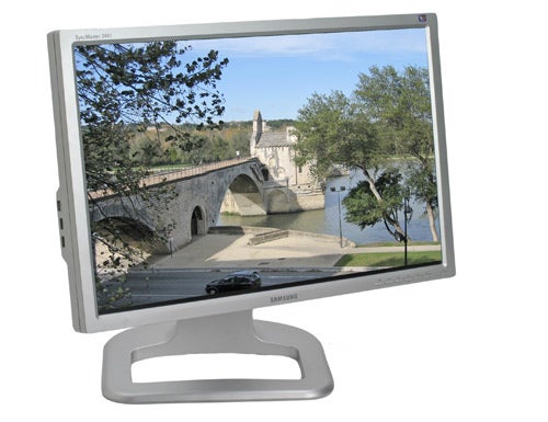 Samsung SyncMaster 244T monitor displaying a vibrant image of a historical stone bridge over a river with trees and a clear sky in the background.