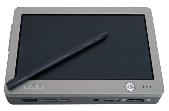OQO model 01+ Tablet Edition with stylus lying on the screen, showcasing the compact design and various ports on the device.