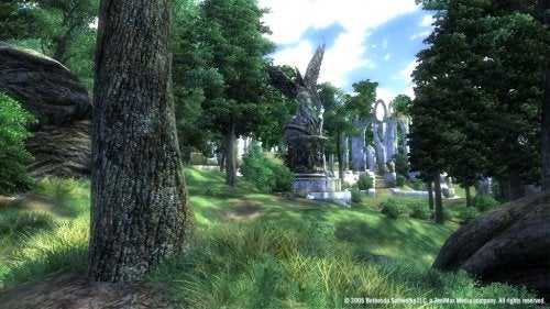 In-game screenshot of a lush green landscape from The Elder Scrolls IV: Oblivion, featuring dense trees, a grassy field, and ancient ruins with a large statue in the background.