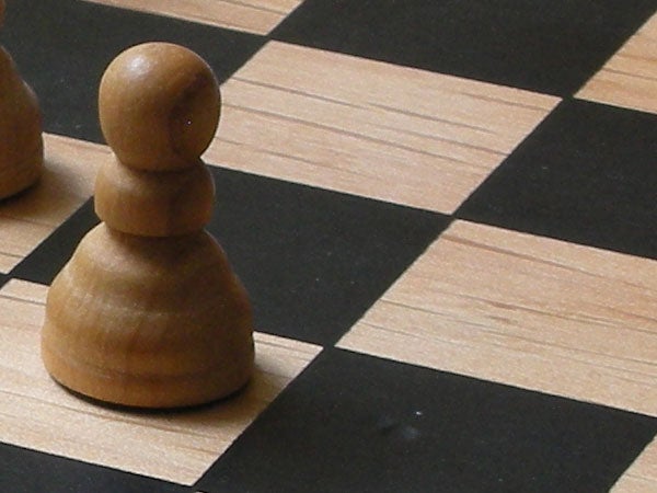 A wooden pawn on a chessboard, showcasing the image quality and close-up capabilities of the Nikon Coolpix S5 camera.