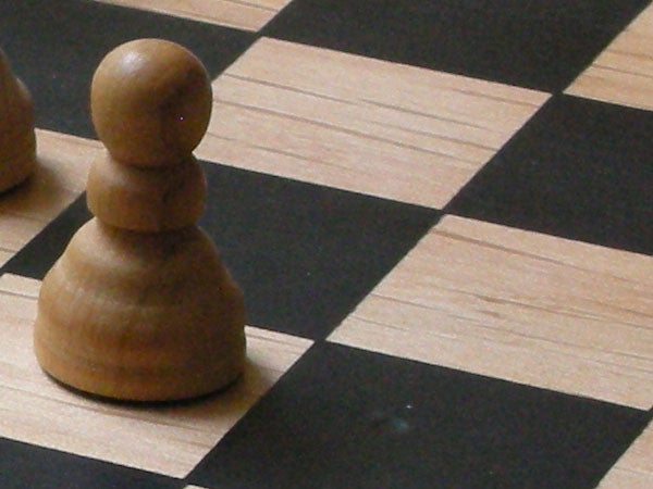 Close-up photo of a single wooden chess pawn on a chessboard, likely taken with a Nikon Coolpix S5 camera showing the camera's depth of field capabilities.