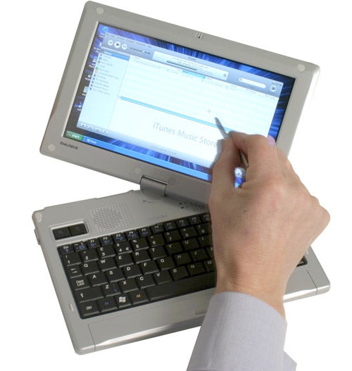 A person using a stylus on the touchscreen display of a Dialogue Flybook convertible laptop with iTunes Music Store on the screen.