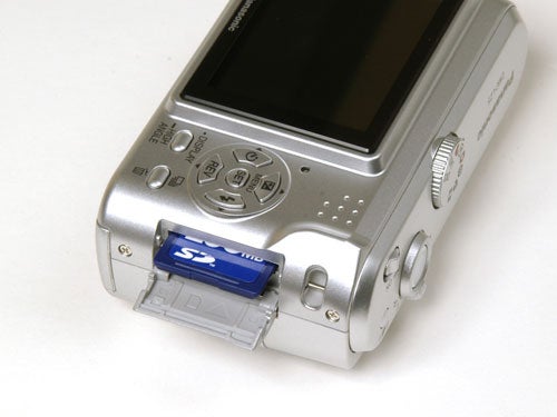 Panasonic Lumix DMC-LZ5 camera with open battery compartment showing an SD memory card inserted.