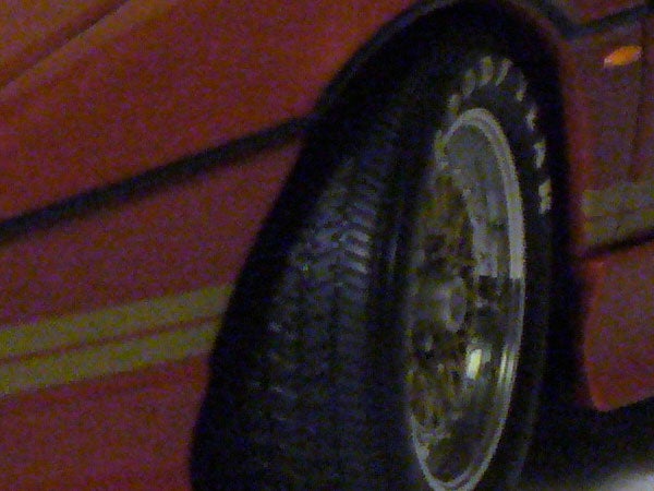 This image is a low-resolution photo showing a blurred side view of a vehicle tire with its pattern partially visible and the sidewall reflecting some light. The context or relevance to Panasonic Lumix DMC-LZ5 is not apparent in the image.