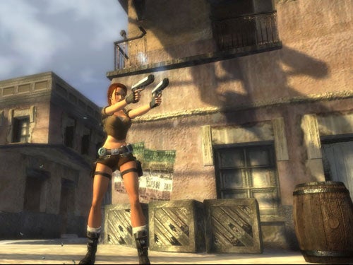 Lara Croft character from Tomb Raider: Legend video game holding two guns with ruined buildings and crates in the background.