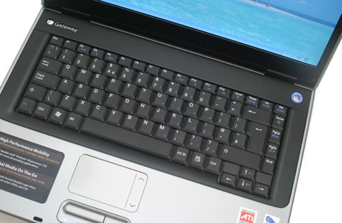 A Gateway MX6640b laptop with the screen displaying a blue wallpaper, focusing on the keyboard and touchpad area, indicative of the product's design and layout.