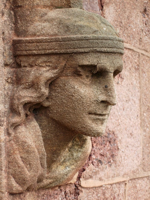 Close-up of a stone bas-relief sculpture of a face on a wall, showing the Nikon Coolpix P4's sharpness and detail capture capabilities.