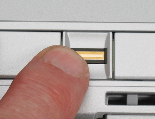 Close-up of a person's thumb inserting a 3G SIM card into the designated slot of a Fujitsu-Siemens LifeBook E8210 notebook.
