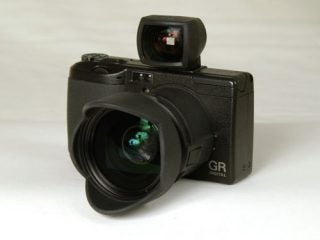 Ricoh GR Digital camera with a black external viewfinder attached to the hot shoe, displayed on a light background.