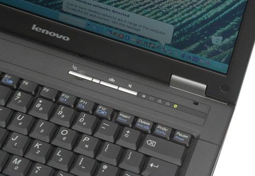 Close-up of a Lenovo 3000 C100 laptop keyboard and screen with a notification for wireless network detection.