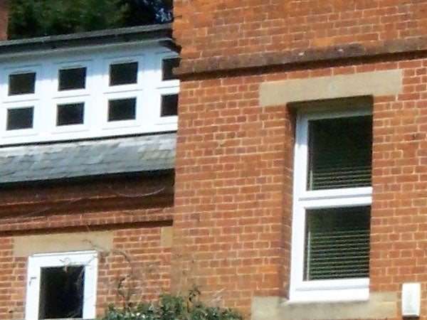 Close-up photograph of a brick building with a focus on the windows, demonstrating the zoom capability of the Kodak EasyShare V610 camera.