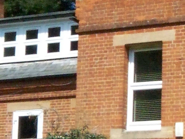 A close-up photo showing the detail of a brick building with windows, demonstrating the Kodak EasyShare V610 camera's zoom capability and image quality.