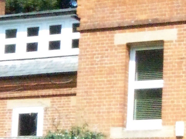 A digital zoomed-in photograph showing the distorted and pixelated details of a brick building with a window.