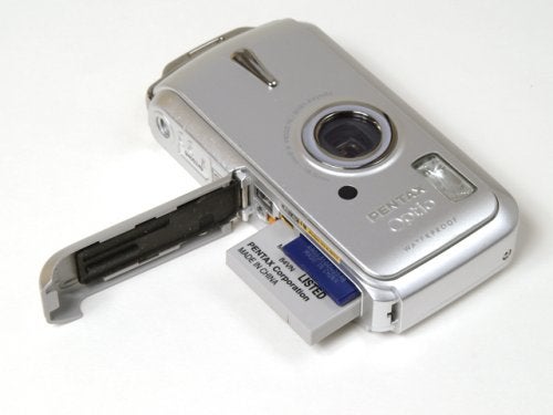 Silver Pentax Optio W10 digital camera with the battery compartment open, revealing a lithium-ion battery.
