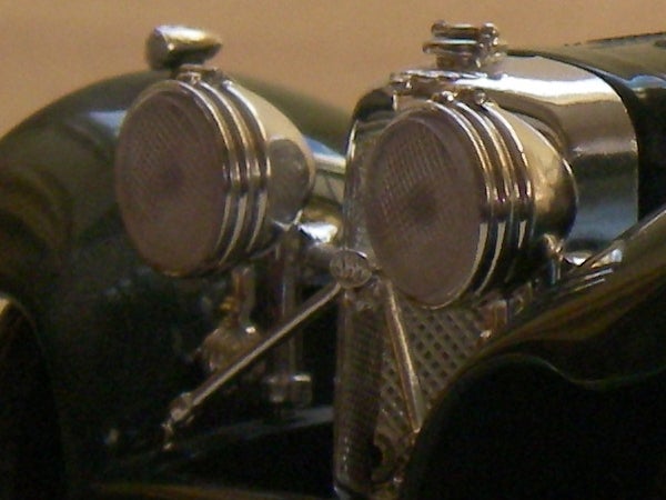 Close-up photo of vintage car headlights with intricate metal detailing.